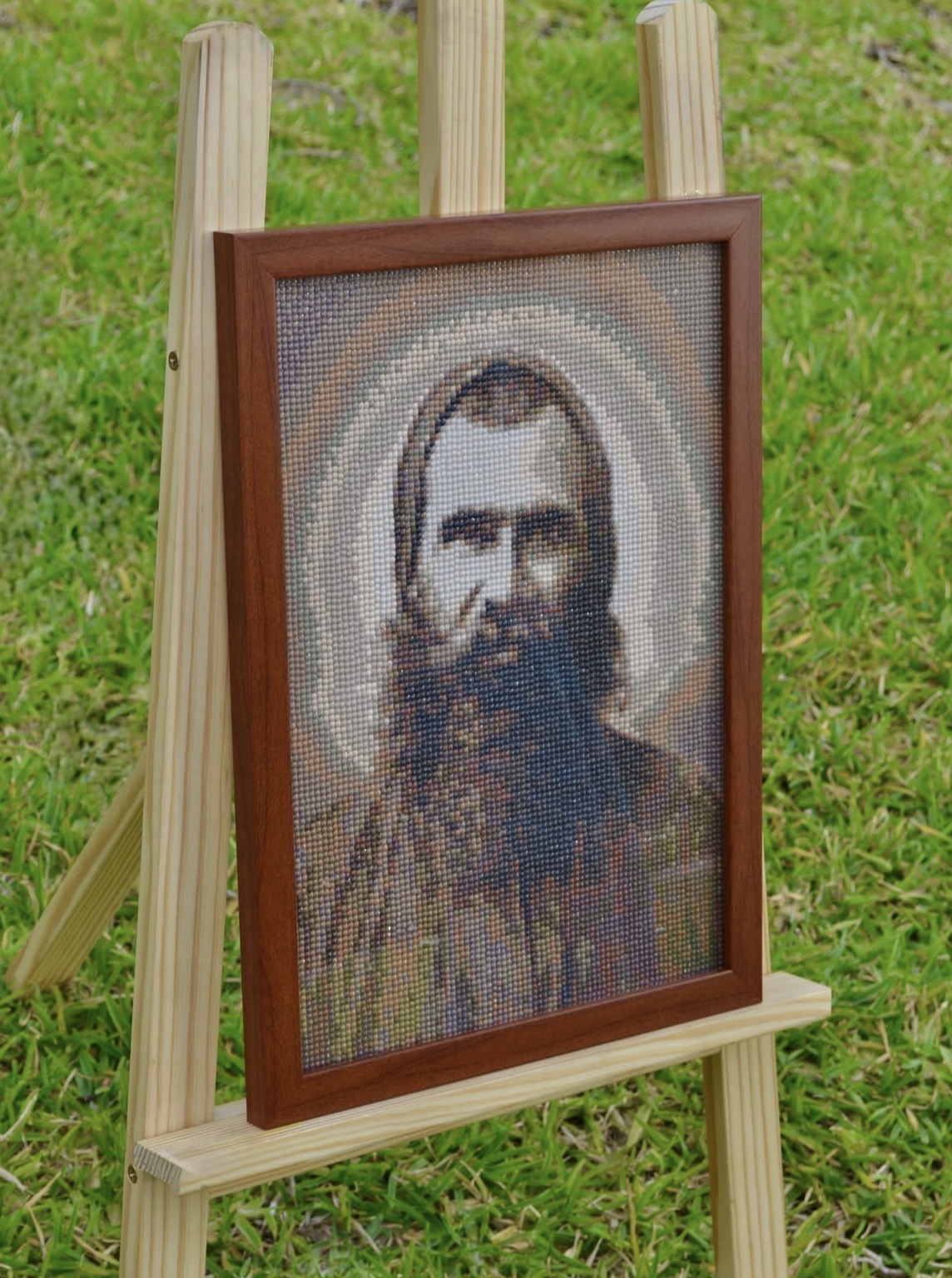 Framed diamond painting of a saint displayed on an easel